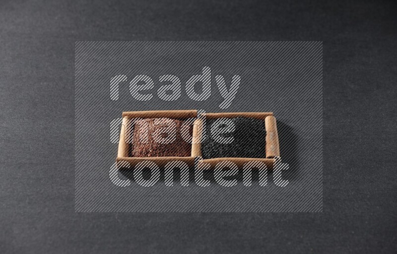 مربعان من أعواد القرفة ممتلئان بحب الرشاد وحبة البركة السوداء علي خلفية سوداء