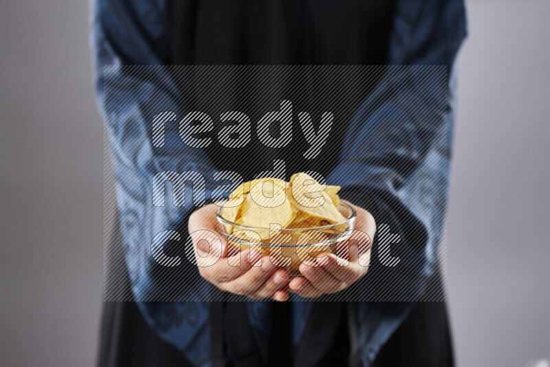 Woman in abaya holding different kinds of snacks in different positions