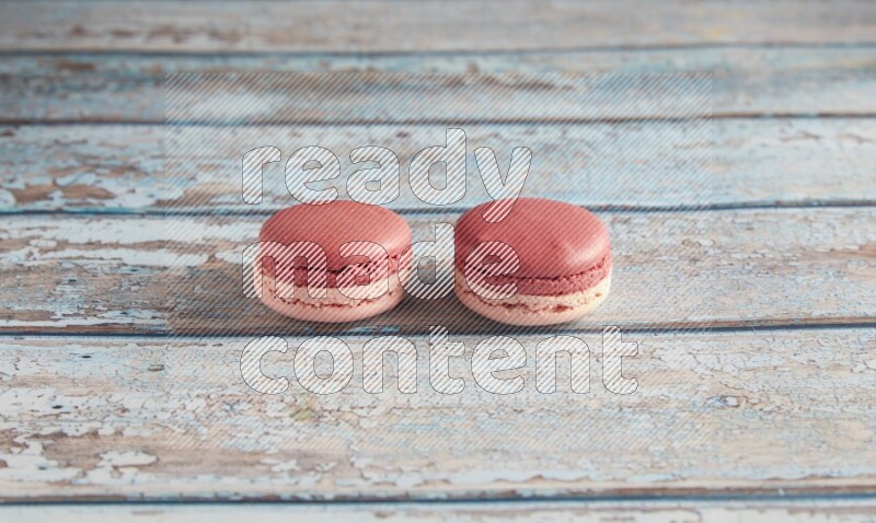 45º Shot of two Pink Litchi Raspberry macarons on light blue wooden background