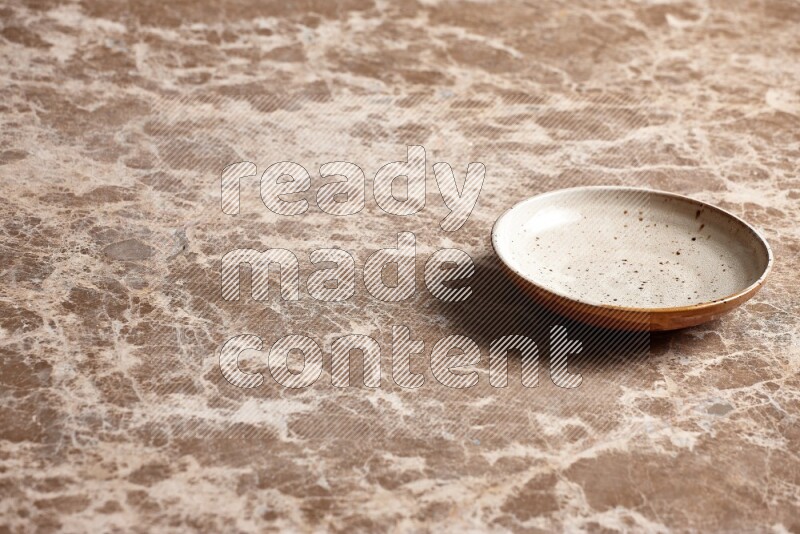 A multicolored pottery plate on beige marble background