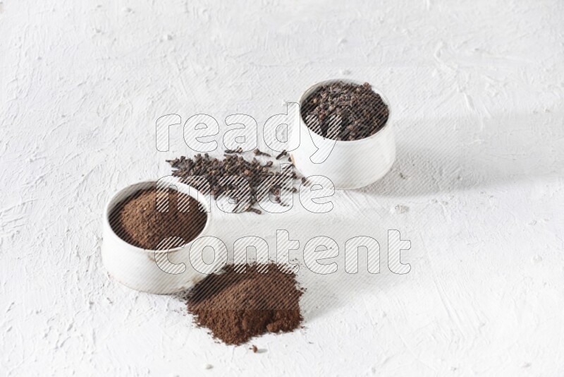 وعاءين من السيراميك بيج اللون، أحدهما مملوء بالقرنفل والآخر مملوء بالبودرة على أرضية بيضاء