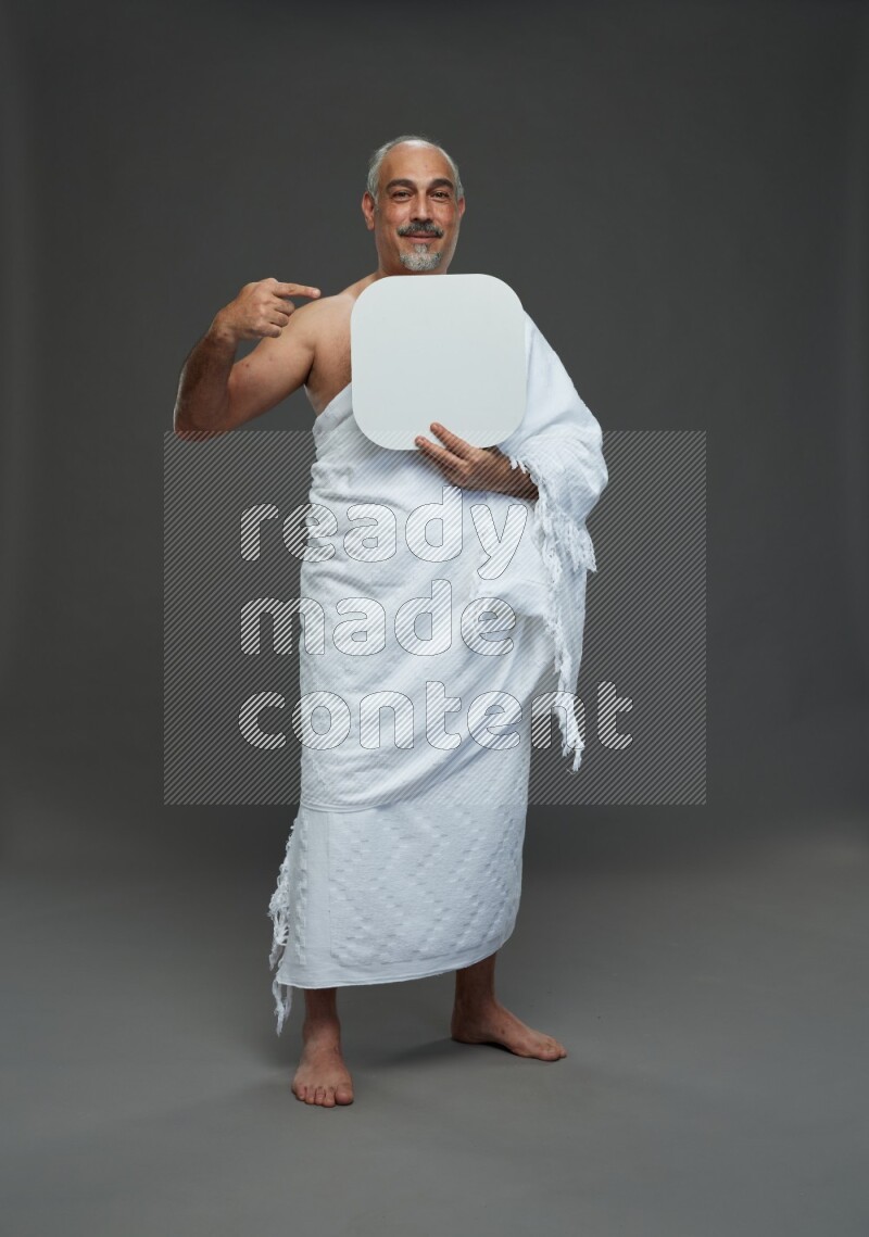 A man wearing Ehram Standing holding social media sign on gray background