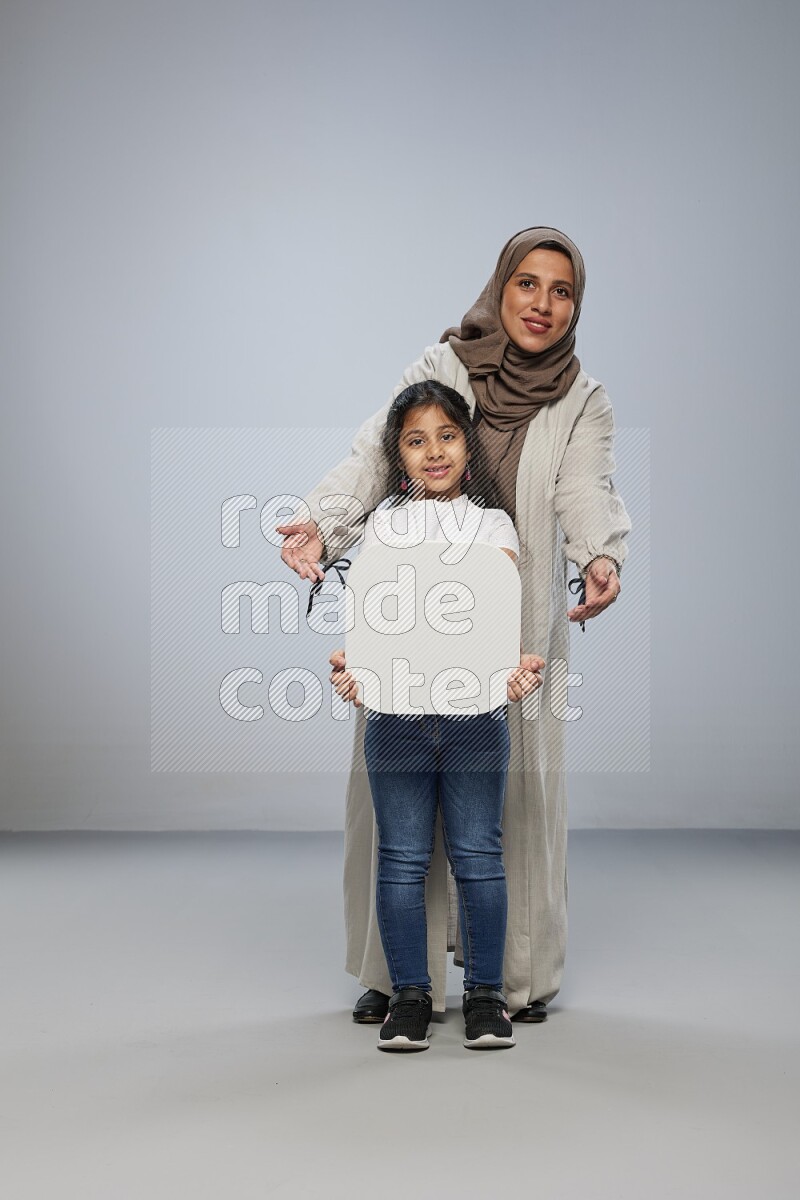 Mom and daughter standing holding social media sign on gray background