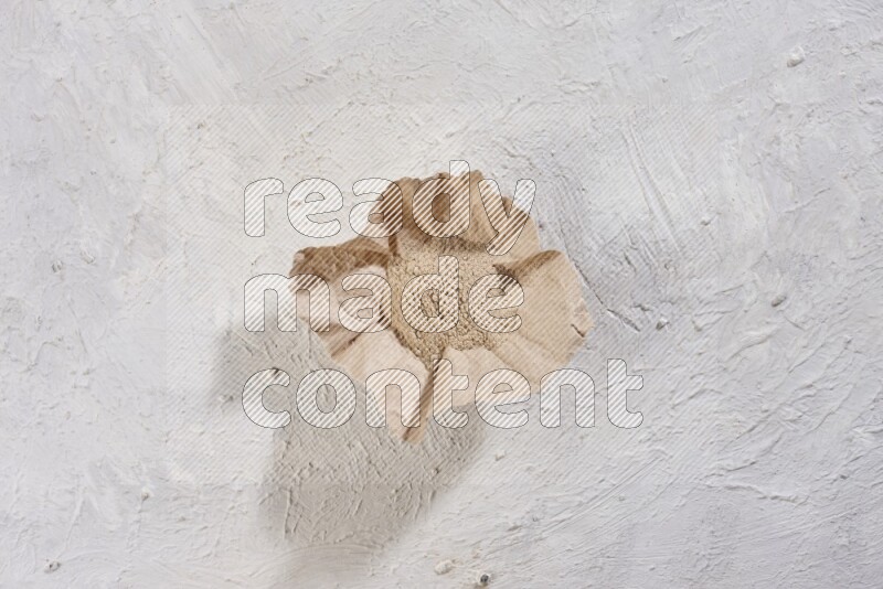 A crumpled piece of paper full of garlic powder placed on a textured white flooring