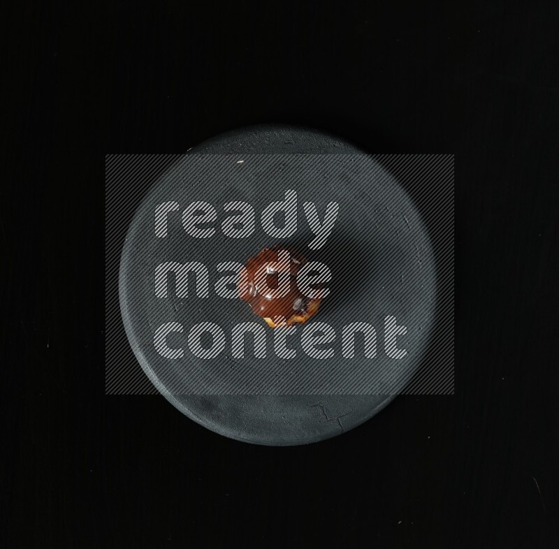 Assorted desserts in a black pottery plate on black background