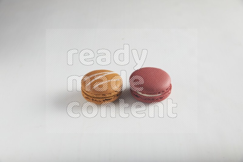 45º Shot of of two assorted Brown Irish Cream, and Red Velvet macarons on white background