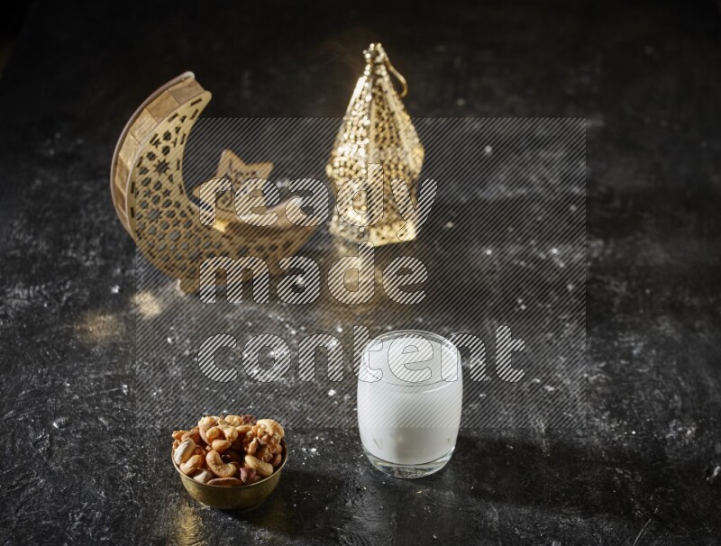 مكسرات في وعاء معدني مع السوبيا بجانب فوانيس ذهبية علي خلفية سوداء