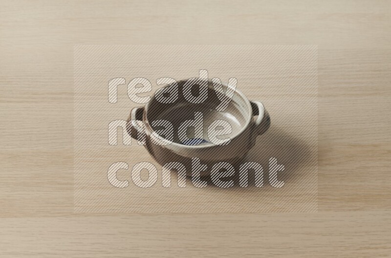A multicolored pottery bowl on light wooden background