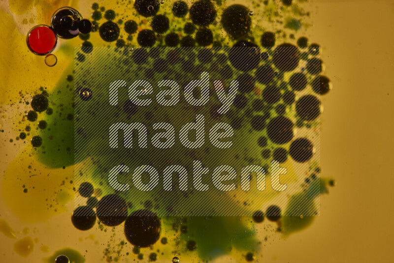 Close-ups of abstract green, black and red watercolor drops on oil Surface on yellow background