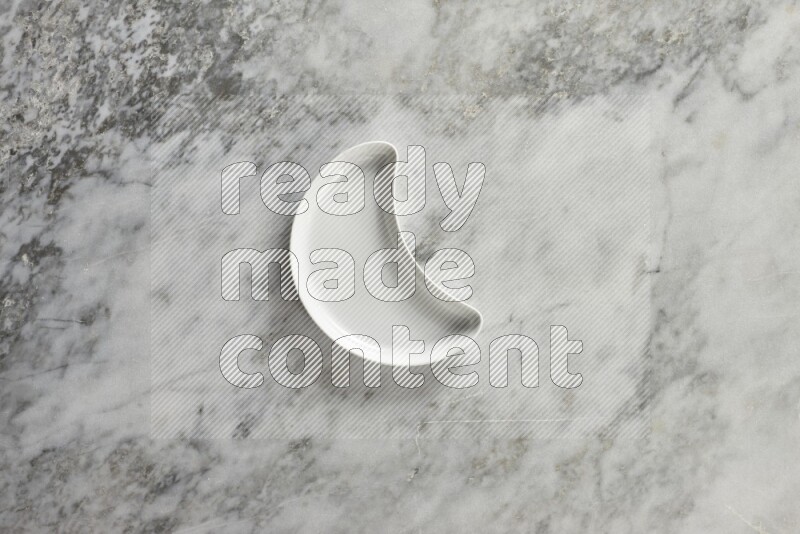 A pottery crescent plate on grey marble background