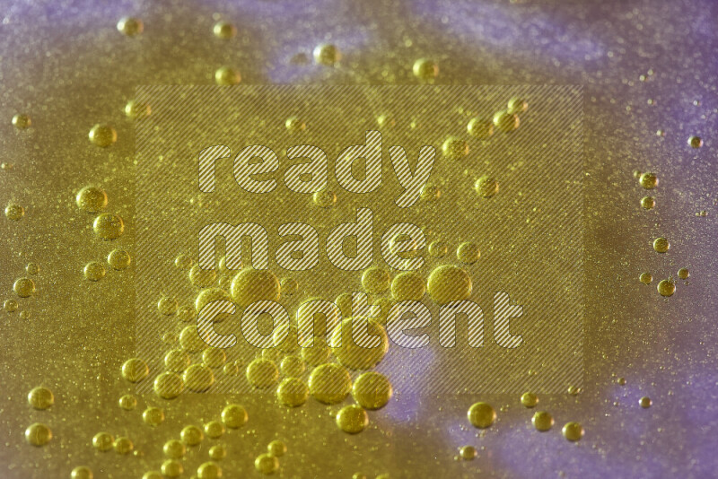 Close-ups of abstract yellow watercolor drops on oil Surface on pink background