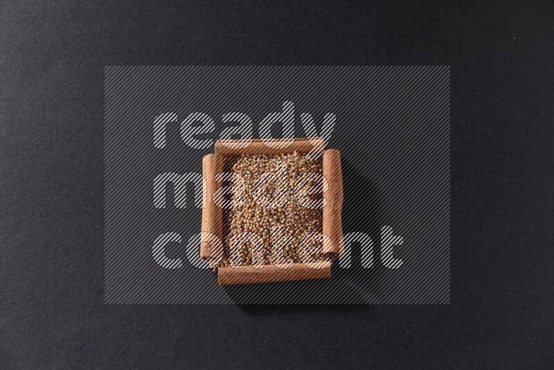 A single square of cinnamon sticks full of mustard seeds on black flooring
