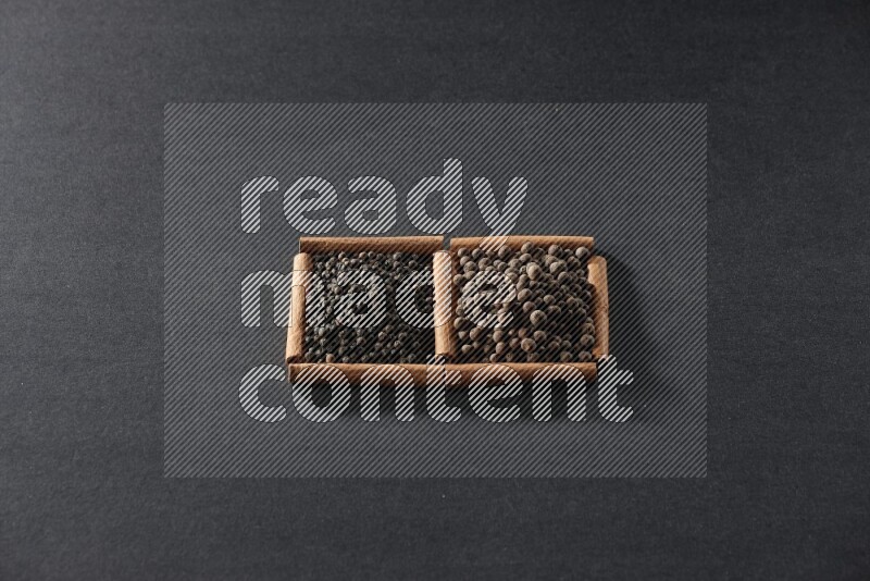 2 squares of cinnamon sticks full of black peppers and allspice on black flooring