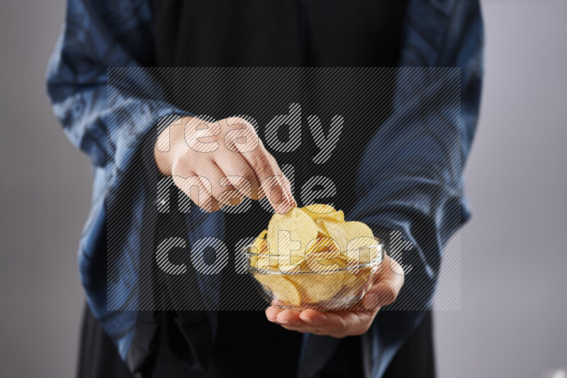 Woman in abaya holding different kinds of snacks in different positions