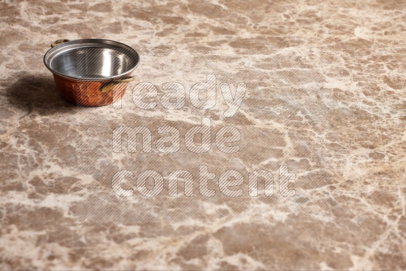 A small copper pot on beige marble background