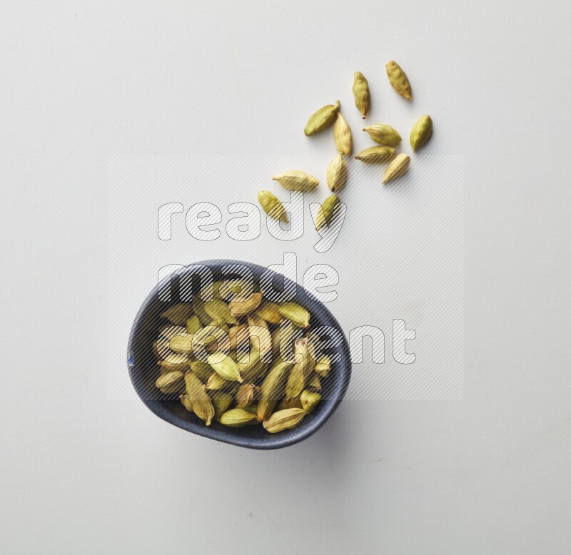 Top-view shot of Cardamon in a container on white background