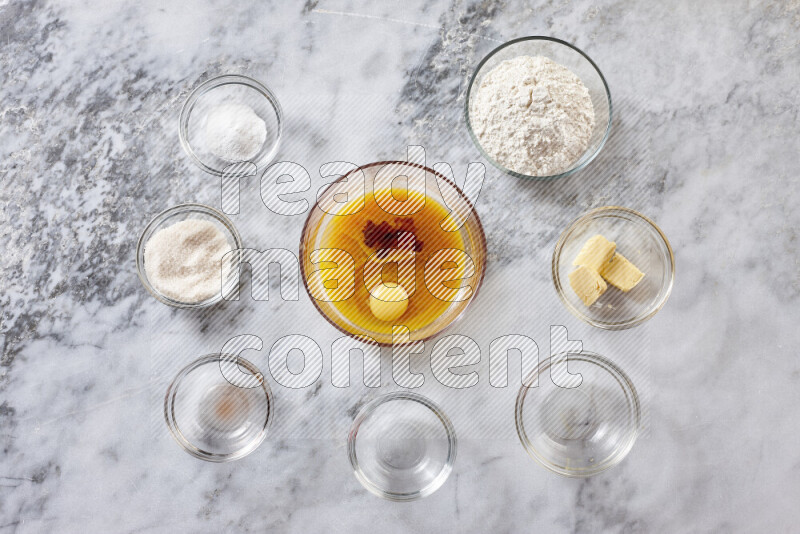 كوكيز خطوة بخطوة بمكوناتها، الدقيق، الزبدة، السكر البني، البيض، الفانيليا، السكر الأبيض، رقائق الشوكولاتة وصودا الخبز على خلفية رخام رمادي