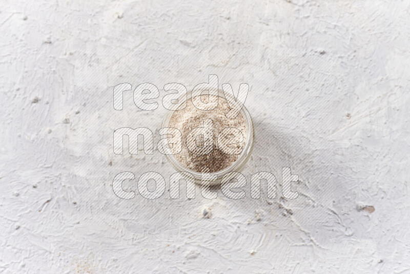A glass jar full of onion powder on white background