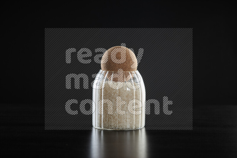 White rice in a glass jar on black background