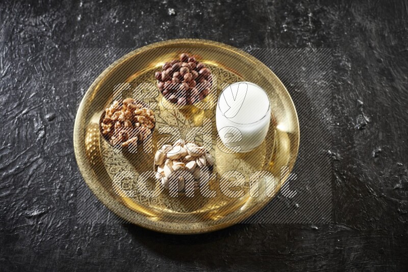 مكسرات في أطباق معدنية مع السوبيا على صينية علي خلفية سوداء