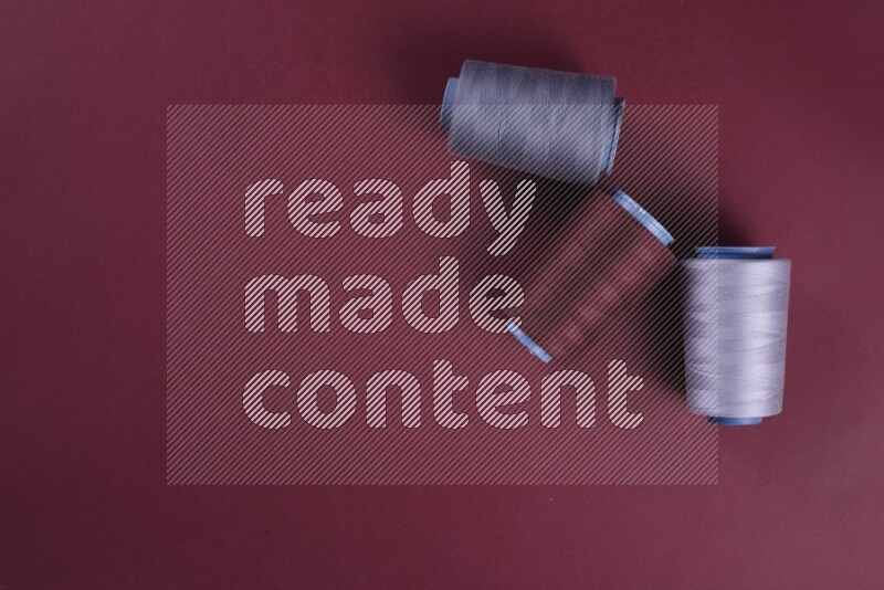 مجموعة من أدوات الخياطة والتفصيل رمادية اللون على خلفية حمراء