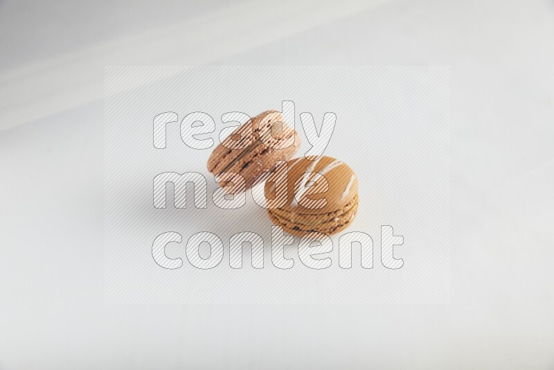 45º Shot of of two assorted Brown Irish Cream, and Brown Hazelnuts macarons on white background