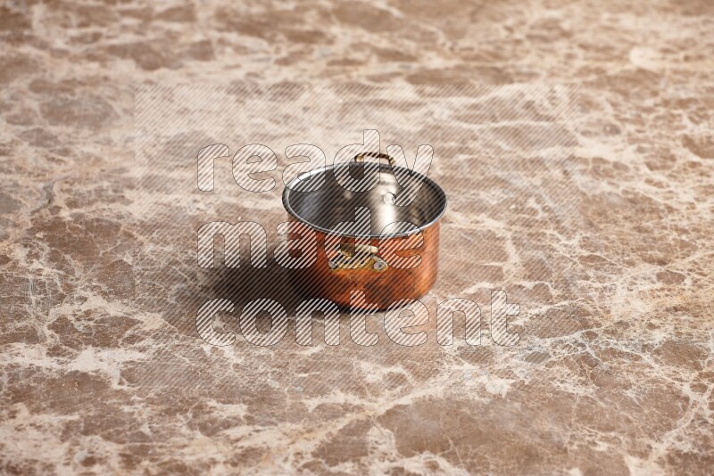 A small copper pot on beige marble background
