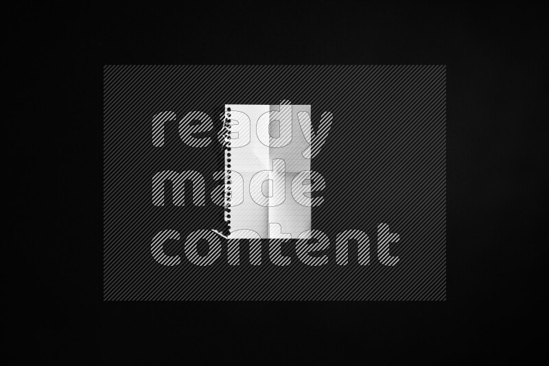 Folded notebook sheet on black background