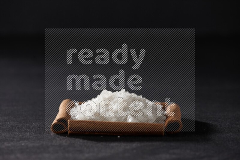 A single square of cinnamon sticks full of salt on black flooring
