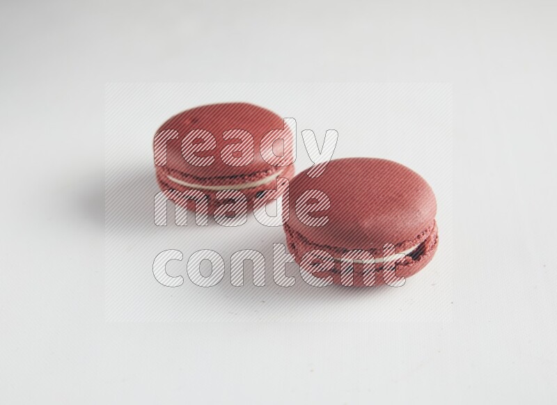 45º Shot of two Red Velvet macarons on white background