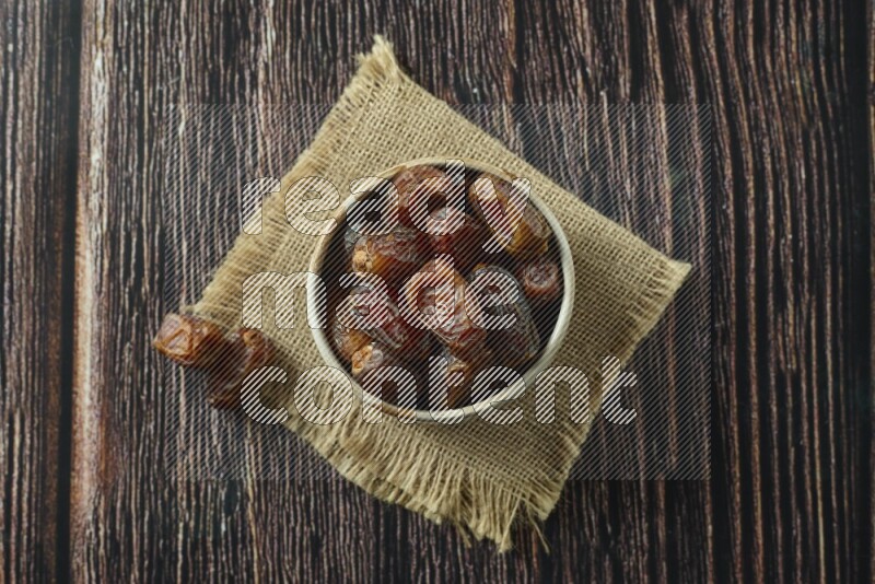 Dates in different bowls (wooden, pottery and glass) on wooden background