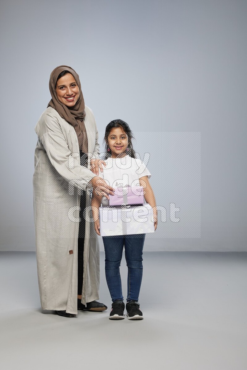A girl giving a gift to her mother on gray background
