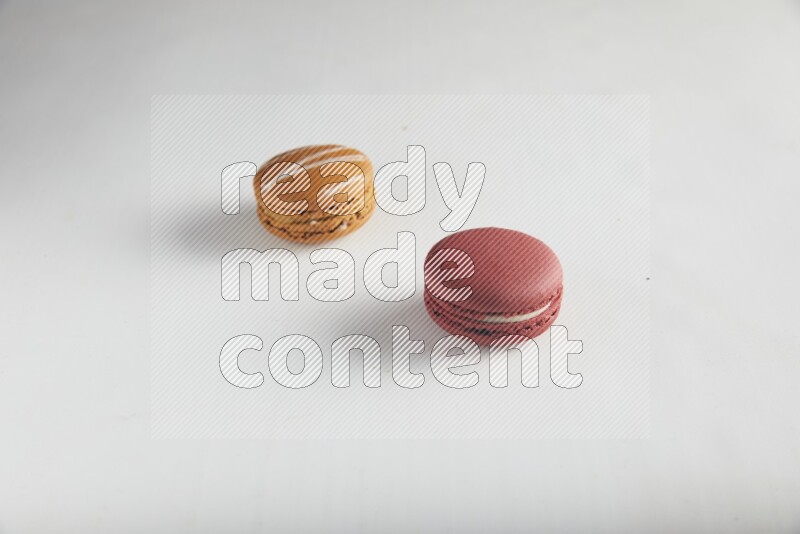 45º Shot of of two assorted Brown Irish Cream, and Red Velvet macarons on white background