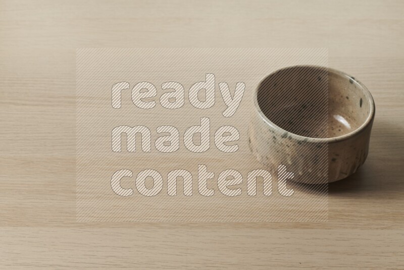 A multicolored pottery bowl on light wooden background