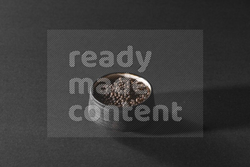 حبوب الفلفل الأسود في وعاء فخاري أسود علي خلفية سوداء