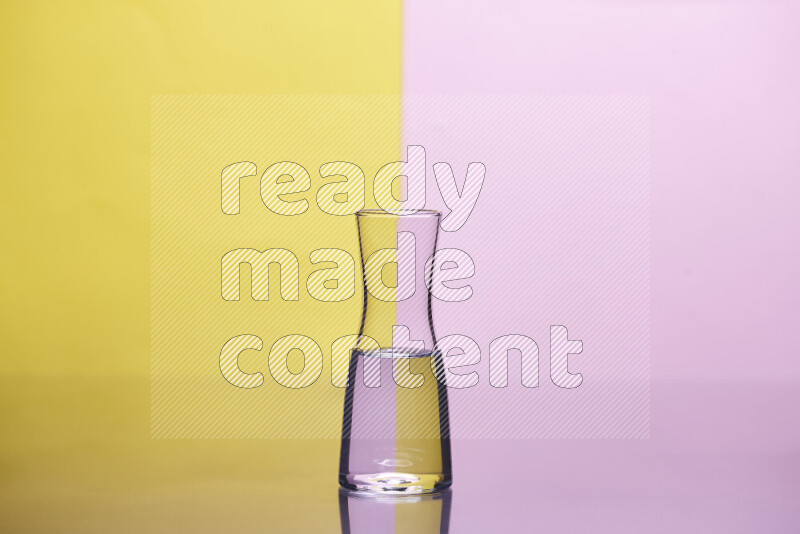 The image features a clear glassware filled with water, set against yellow and rose background
