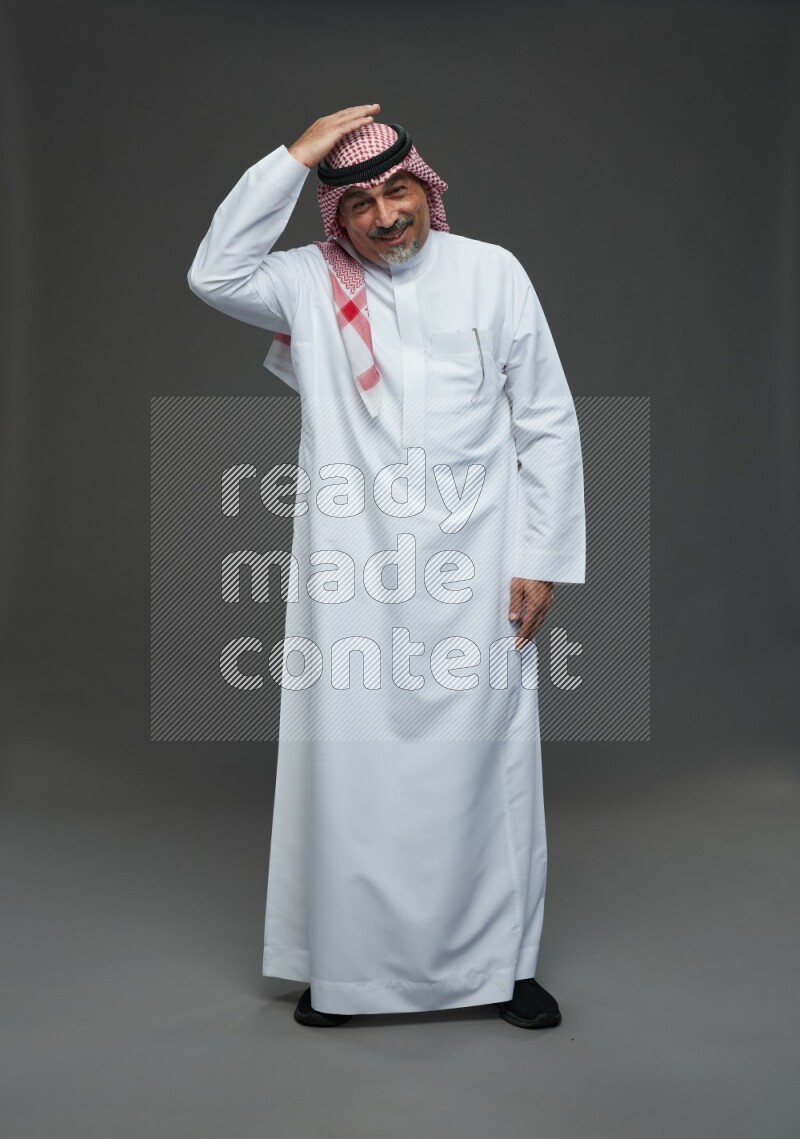 Saudi man with shomag Standing Interacting with the camera on gray background