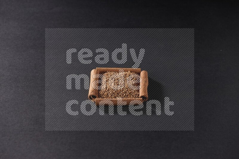 A single square of cinnamon sticks full of mustard seeds on black flooring