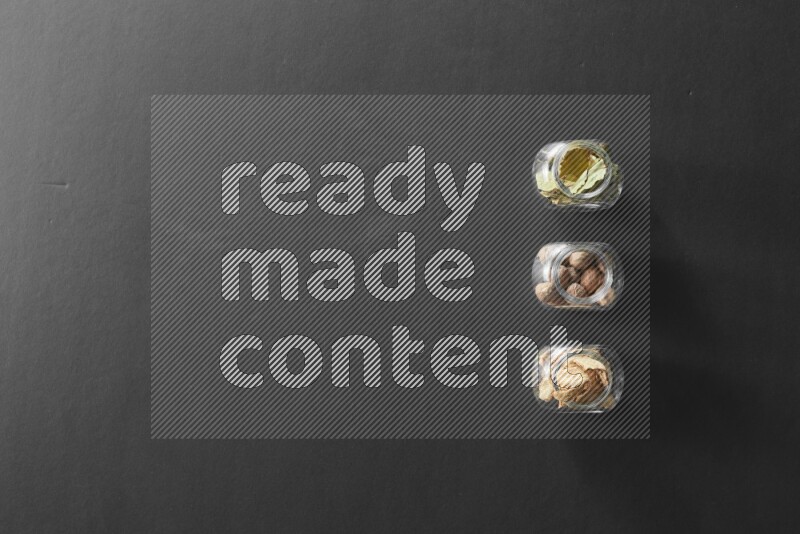 أوراق الغار وزنجبيل مجفف وجوزة الطيب في أوعية زجاجية علي خلفية سوداء