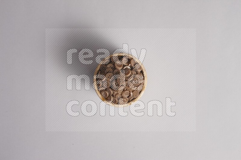 Colored buttons in a beige pottery bowl on grey background