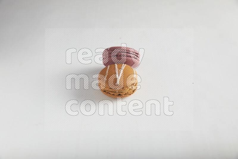 45º Shot of of two assorted Brown Irish Cream, and Red Poppy Flower macarons on white background