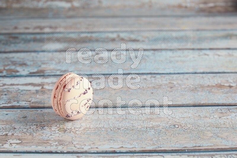45º Shot of pink orange blossom macaron on light blue wooden background