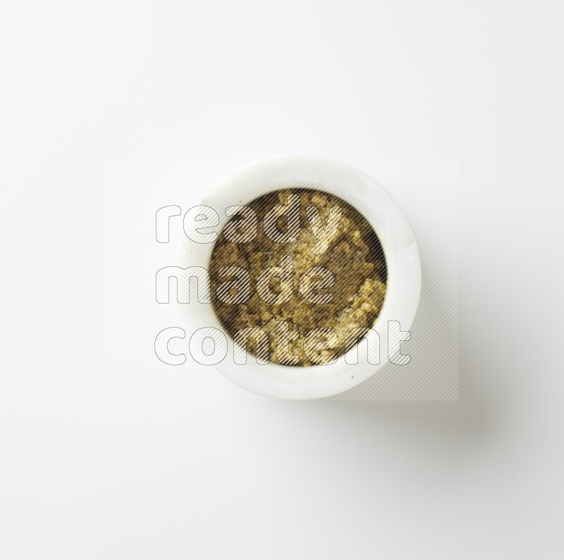 small white ceramic round bowl filled with pesto paste on a white counter top