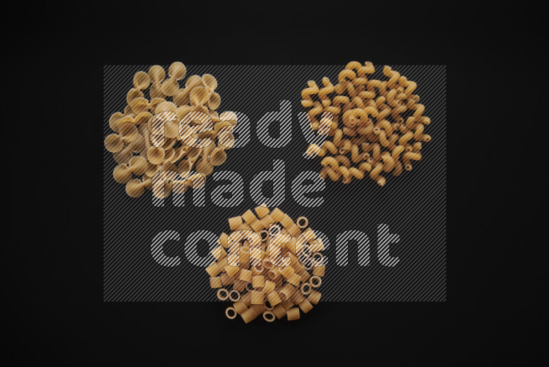 Different pasta types in bunches on black background
