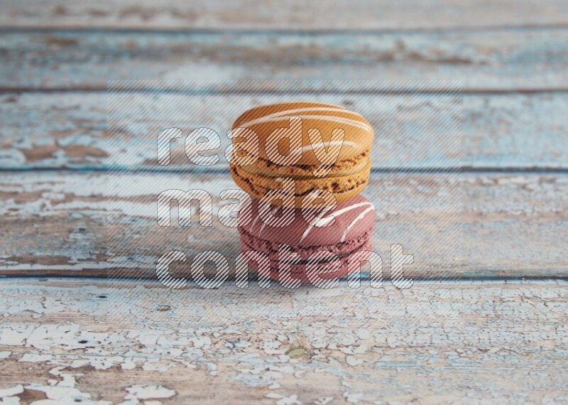 45º Shot of of two assorted Brown Irish Cream, and Red Poppy Flower macarons  on light blue background