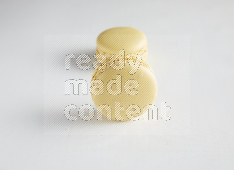 45º Shot of two Yellow Vanilla macarons on white background