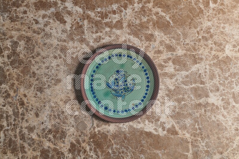 A decorative pottery plate on beige marble background