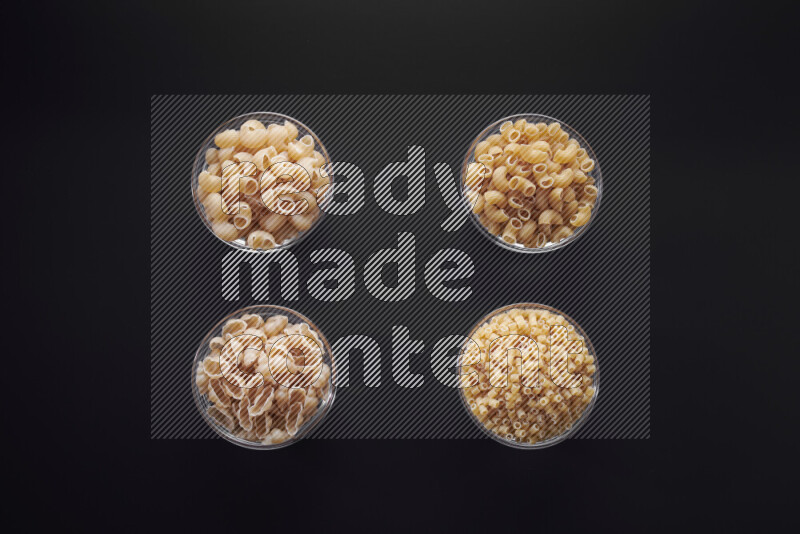 أنواع مختلفة من المعكرونة في وعاء زجاجي علي خلفية سوداء