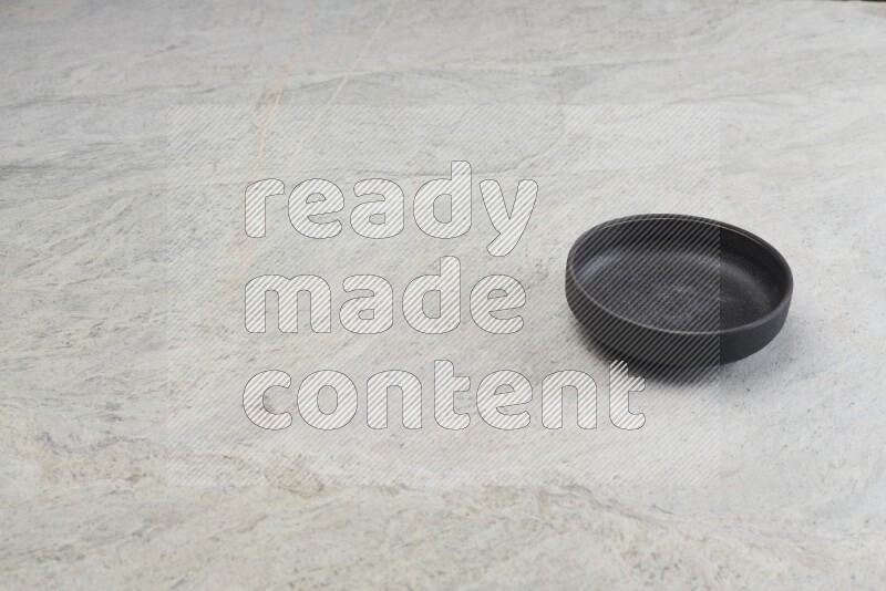 A black pottery oven bowl on grey marble background