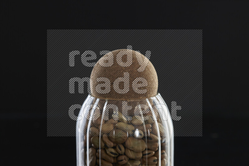 Fava beans in a glass jar on black background